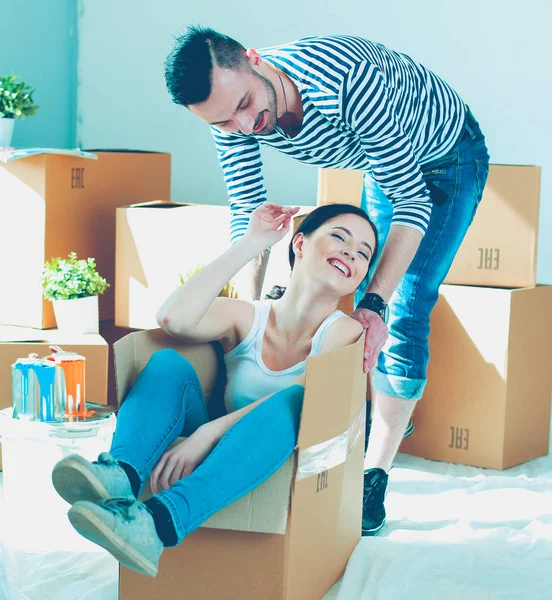 Feliz jovem casal desembalagem ou embalagem caixas e se mudar para uma nova casa — Fotografia de Stock