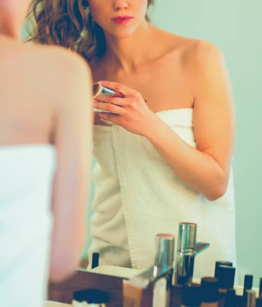 Młoda kobieta patrzy w lustro i nakłada makijaż. — Zdjęcie stockowe
