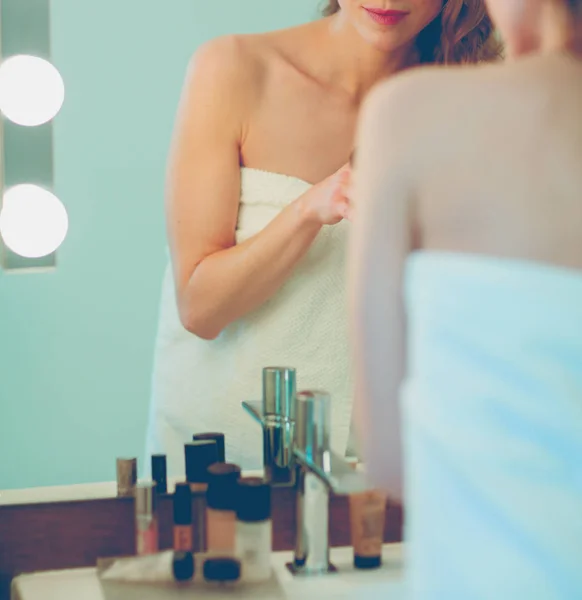 Fiatal nő néz a tükörbe, és smink fel — Stock Fotó