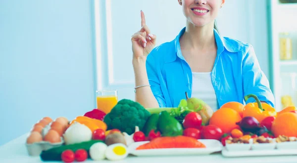 Junge und süße Frau sitzt am Tisch voller Obst und Gemüse im hölzernen Innenraum — Stockfoto