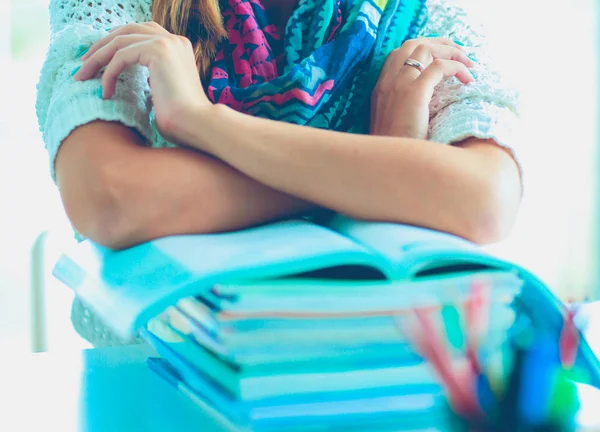 Jonge vrouw zit aan een bureau tussen de boeken — Stockfoto