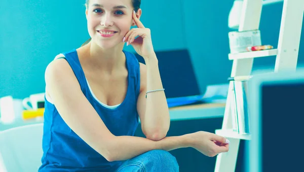 Jonge vrouw zitten op de balie in kantoor — Stockfoto