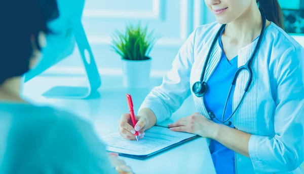 Médico y paciente discutiendo problemas médicos en una sala de consulta del hospital. Doc rellenando un formulario de pacientes — Foto de Stock