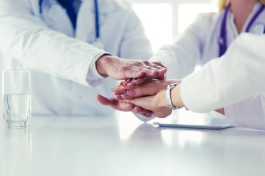 Doktorlar el ele tutuşup yakın çekim yapıyor.