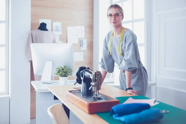 Skapa nya stilar. Glada ung kvinna sy medan hon sitter på sin arbetsplats i mode verkstad — Stockfoto