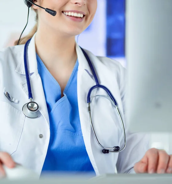 Young practitioner doctor working at the clinic reception desk, she is answering phone calls and scheduling appointments — Stock Photo, Image