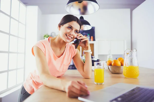 Jeune femme dans la cuisine avec ordinateur portable à la recherche de recettes, souriant. Concept de blogueur alimentaire — Photo