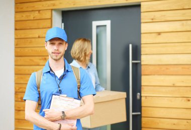Mavi üniformalı gülümseyen kurye servis konseptine paket kutusu teslim eden teslimatçı. Mavi üniformalı gülümseyen teslimatçı.