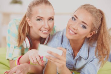 Açık kafede akıllı telefon kullanan iki genç kız.