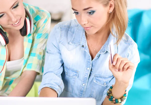 Two young female sisters sitting on sofa, in the living room, at home, making shopping online on digital tablet, holding a credit card — Stock Photo, Image
