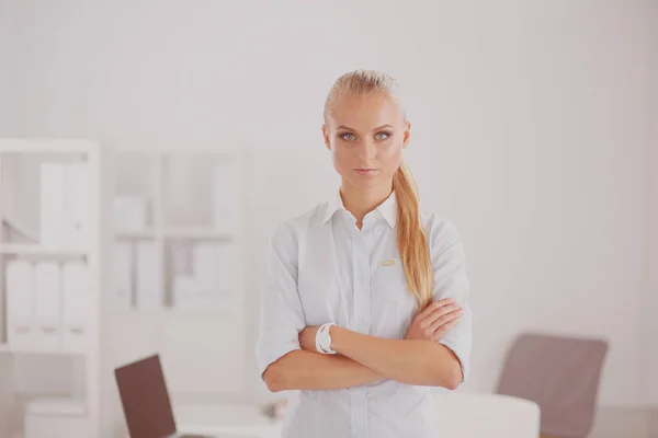 Attraktiv ung affärskvinna står nära skrivbordet på kontoret — Stockfoto