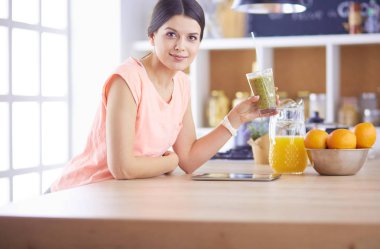 Mutfakta dijital tablet kullanan güzel genç bir kadın.