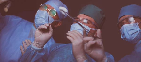 Group of surgeons at work in operating theater toned in blue. Medical team performing operation — Stock Photo, Image