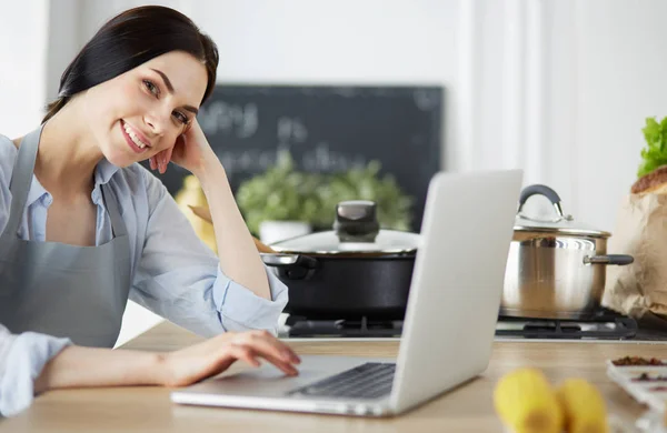 Happy woman in the kitchen reading he news on her laptop — Stock Photo, Image