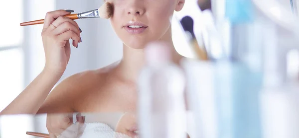 Uma foto de uma jovem mulher aplicando pó facial no banheiro — Fotografia de Stock