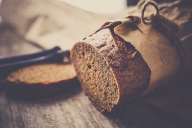 Tahta masanın üzerinde kağıda sarılı bir somun ekmek.