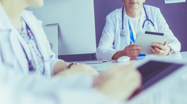 Ciddi bir tıbbi ekip parlak bir ofiste dizüstü bilgisayar kullanıyor.