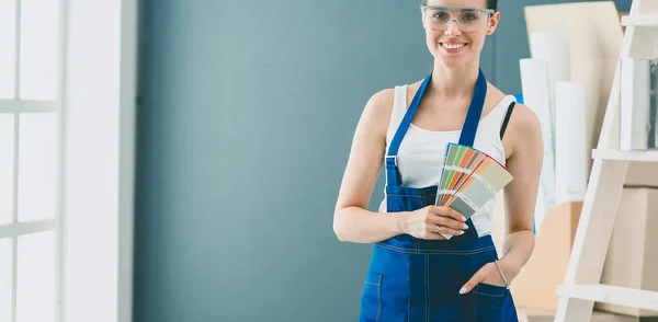 Young woman holding a color swatch with a painter painting . — Stock Photo, Image