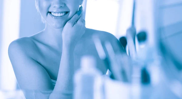 Young woman in bathrobe looking in bathroom mirror — Stock Photo, Image