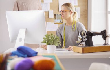 Masasında dikiş makinesi olan bir fabrikada genç ve güzel bir kız.
