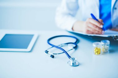 Kadınların elleri bir kağıt parçasına yazı yazıp masasında kalem bırakırlar.