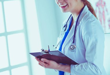 Kadın doktor hastanede dosyayla bekliyor.