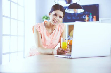 Mutfakta dizüstü bilgisayara benzeyen tariflerle gülümseyen genç bir kadın. Gıda blogcusu kavramı