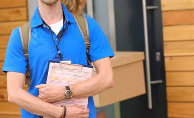 Mavi üniformalı gülümseyen kurye servis konseptine paket kutusu teslim eden teslimatçı. Mavi üniformalı gülümseyen teslimatçı.