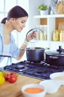 Mutfakta sobanın yanında duran genç bir kadın.