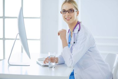 Hastanede masasında oturan genç bir kadın doktorun portresi.