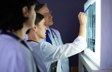 Bir grup doktor bir klinikte röntgenleri inceliyor, teşhis koymayı düşünüyorlar.