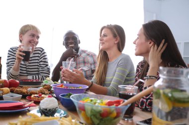 Ahşap masada otururken birlikte yemek yiyen bir grup insanın üst düzey görüntüsü. Masada yemek var. İnsanlar fast food yiyor..