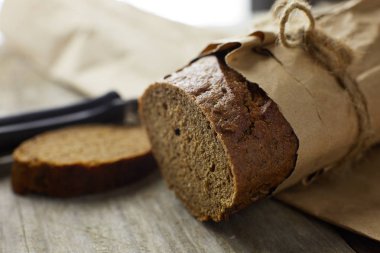 Tahta masanın üzerinde kağıda sarılı bir somun ekmek.