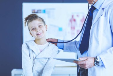 Steteskoplu kız ve doktor kalp atışlarını dinliyor.