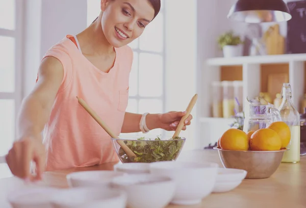 Uśmiechnięta młoda kobieta mieszająca świeżą sałatkę w kuchni. — Zdjęcie stockowe