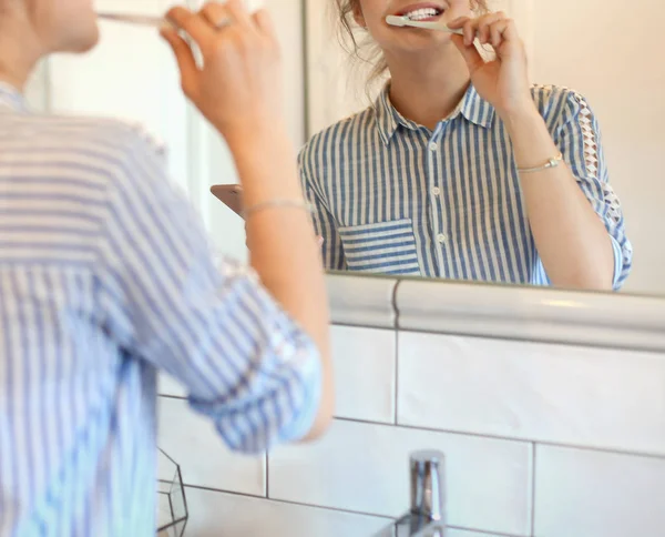 Молодая красивая женщина чистит зубы перед зеркалом — стоковое фото
