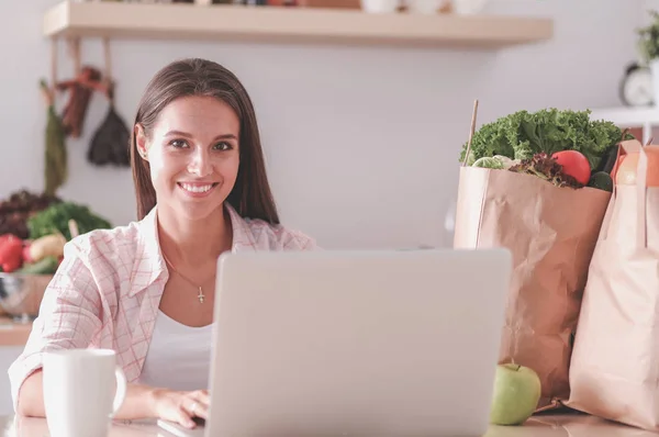 Mujer sonriente compras en línea utilizando tableta y tarjeta de crédito en la cocina. Mujer sonriente —  Fotos de Stock