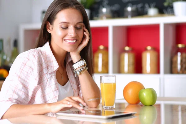 Молода жінка на кухні, використовуючи її ipad. Молода жінка — стокове фото