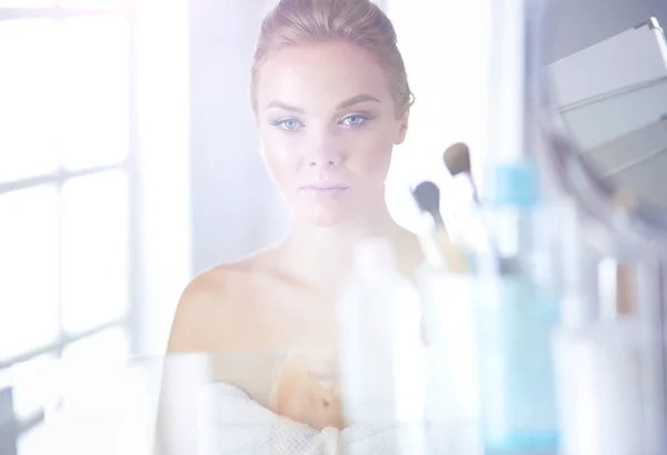 Jonge vrouw in badjas op zoek in badkamer spiegel — Stockfoto