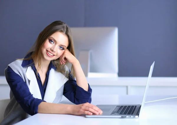 Joven empresaria confiada trabajando en el escritorio de la oficina y escribiendo con una computadora portátil — Foto de Stock