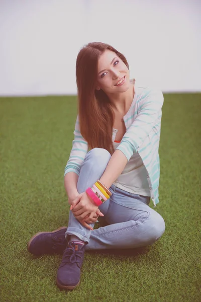 Una hermosa chica está sentada en un banco del parque sobre un fondo de naturaleza verde —  Fotos de Stock