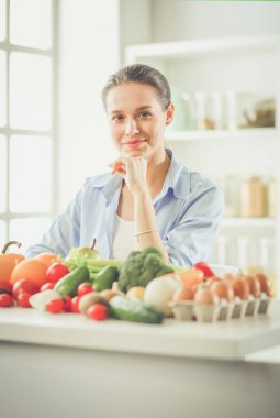 Ahşap iç kısımda meyve ve sebze dolu masada oturan genç ve tatlı bir kadın..