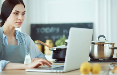 mutlu bir kadın mutfakta o onu laptop haber okuma