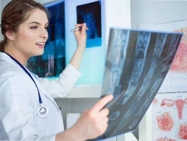 Jonge professionele vrouwelijke arts die patiënten röntgenfoto onderzoekt — Stockfoto
