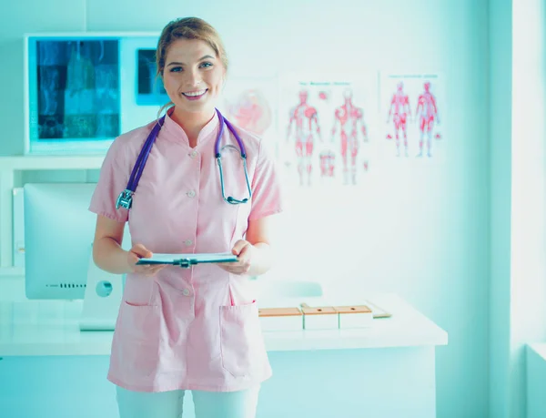 Sorridente medico donna con una cartella in uniforme in piedi in ospedale — Foto Stock