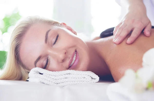 Ung kvinna i spa salong, få stenar massage — Stockfoto