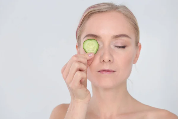 Young beautiful woman with cucumber slices on white background. — Stock Photo, Image