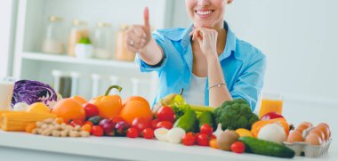 Ahşap iç kısımda meyve ve sebze dolu masada oturan genç ve tatlı bir kadın..