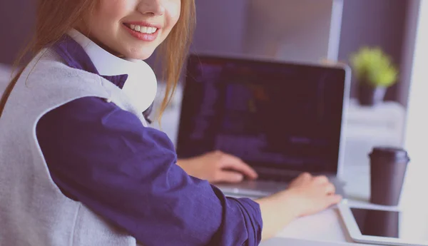 Молода впевнена бізнес-леді, що працює за офісним столом і друкує з ноутбуком — стокове фото