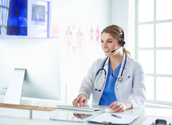 Jovem médico praticante que trabalha na recepção da clínica, ela está atendendo telefonemas e agendando consultas — Fotografia de Stock